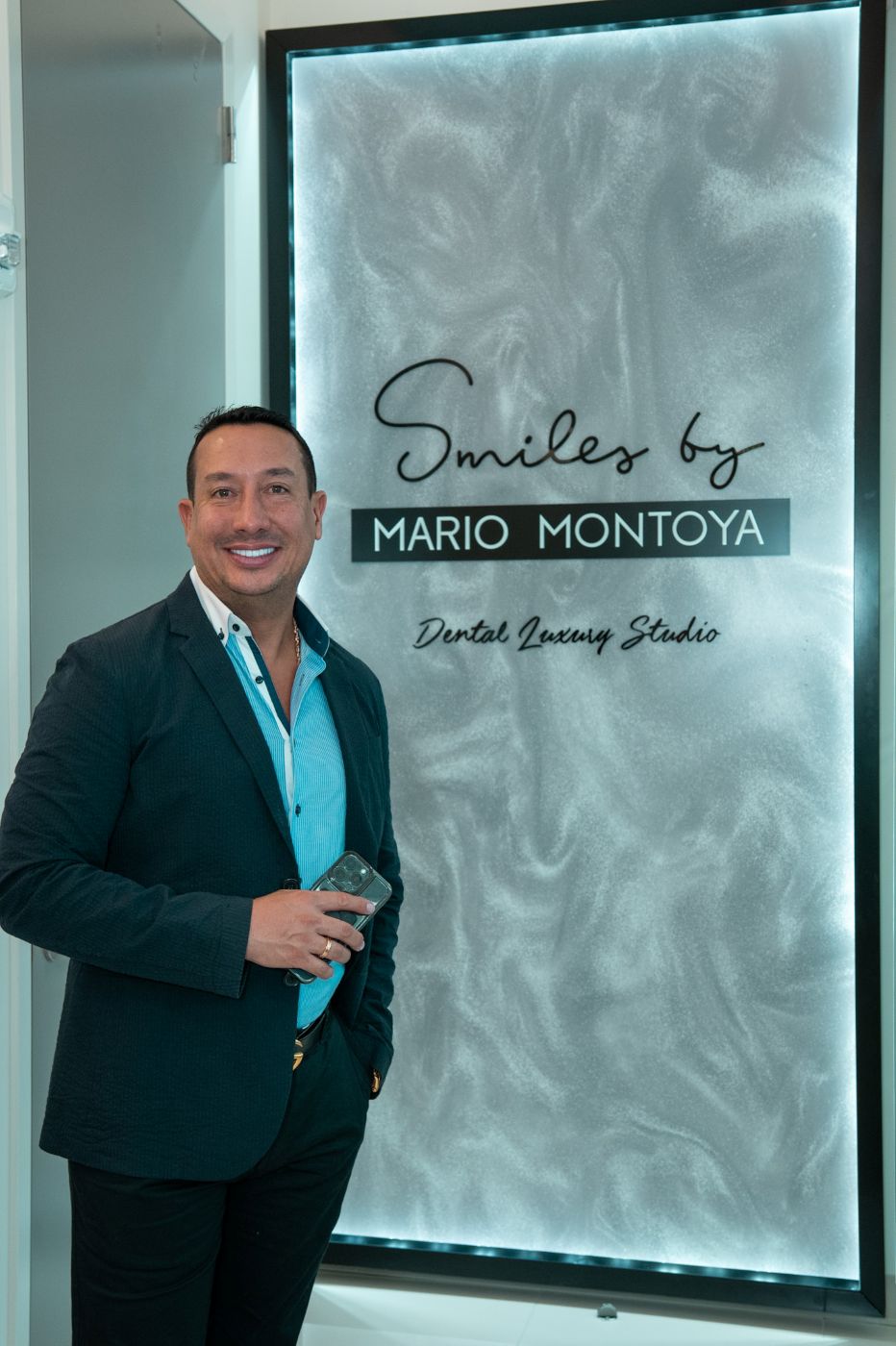 Dr. Mario Montoya standing inside the Smiles by Mario Montoya dental practice, with the practice signage behind him