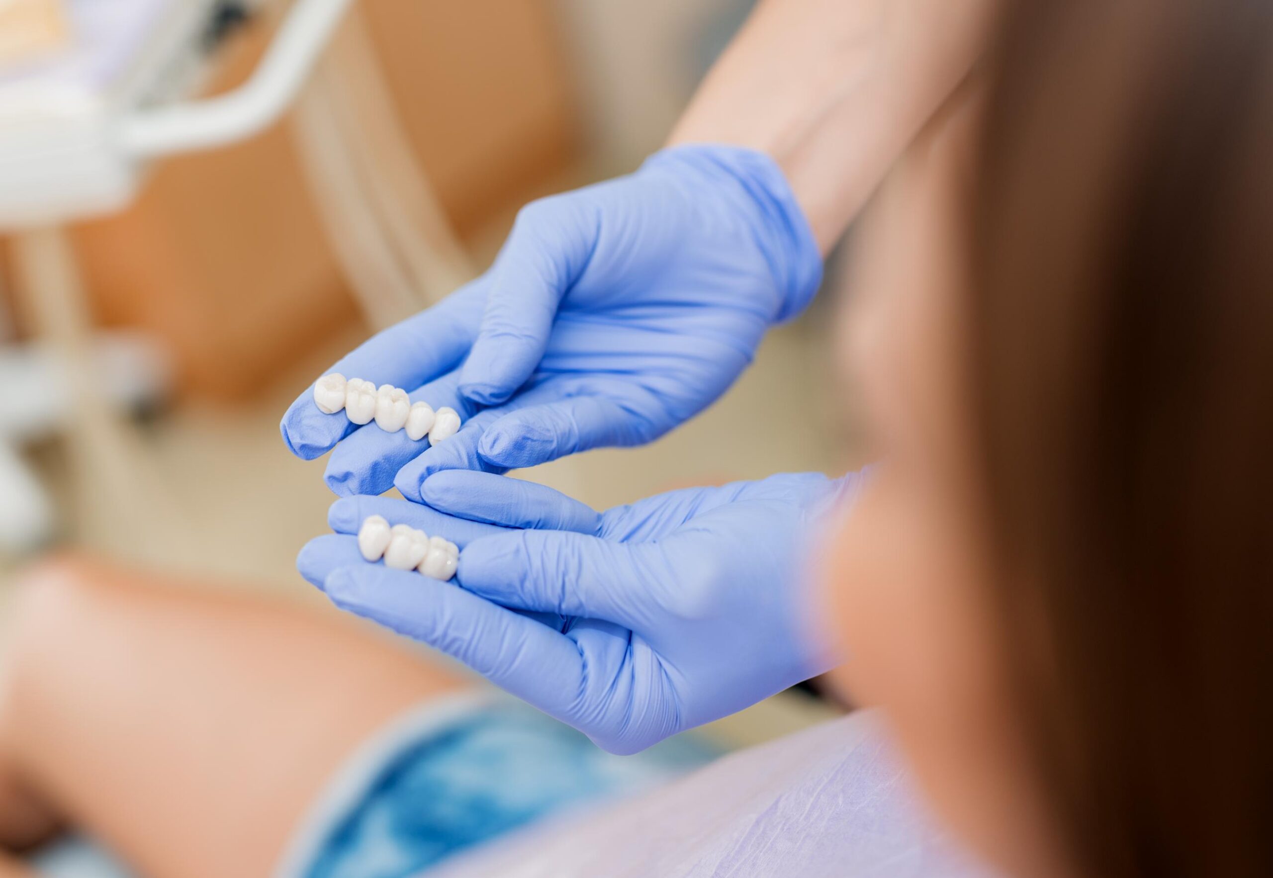 Dental professional holding two tooth-colored dental bridges to demonstrate restorative tooth replacement options
