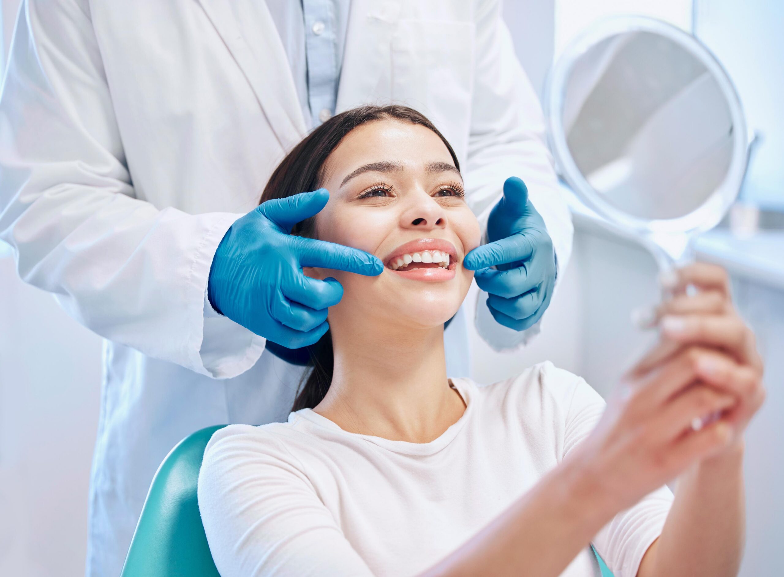 Woman reclining in a dental chair while a dental professional examines her teeth during a dental appointment