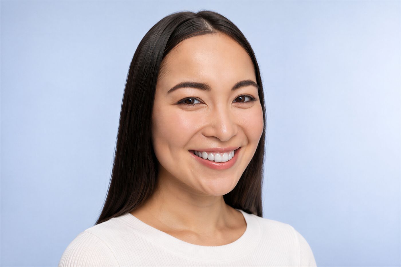Smiling woman with dark hair displaying her teeth, representing natural-looking cosmetic smile design