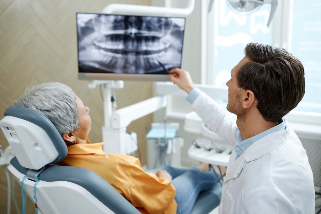 Dentist reviewing dental X-ray results with an older patient during a treatment planning consultation