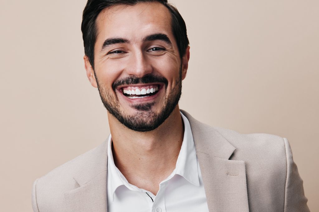 Smiling man with a neatly trimmed beard, illustrating a natural-looking result in cosmetic smile design